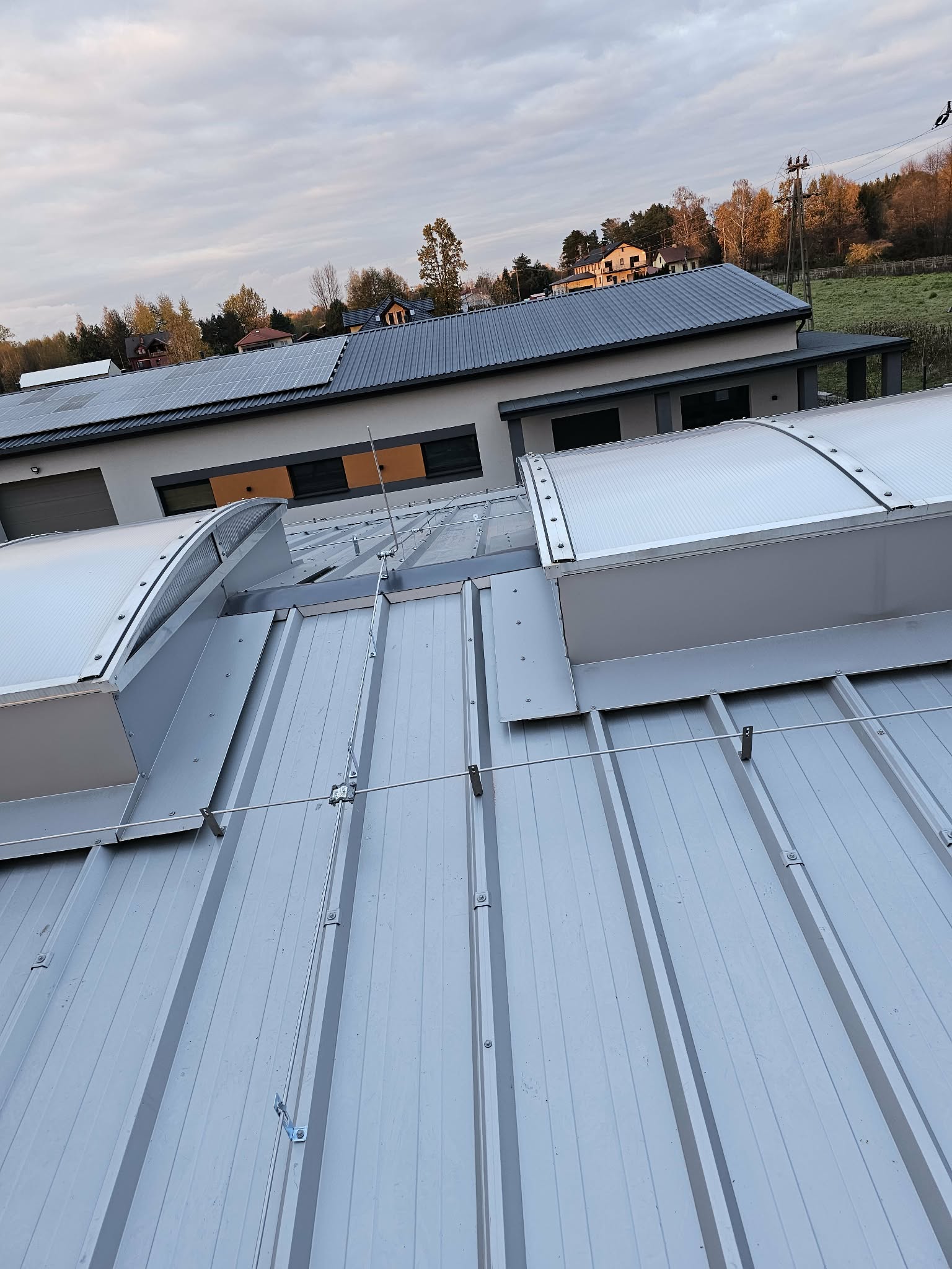 Metalowy dach z łukowymi świetlikami i widocznymi elementami instalacji